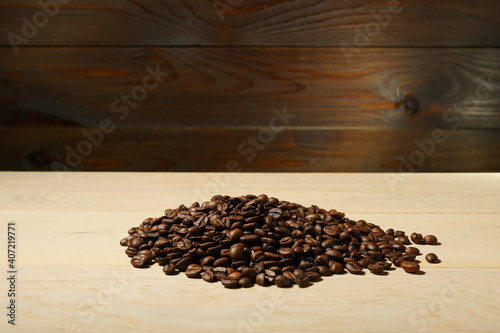 pile of coffee beans is on a wooden background