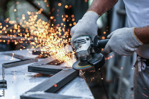 the hands of the master saw the metal with a grinder. metal works in the workshop close up