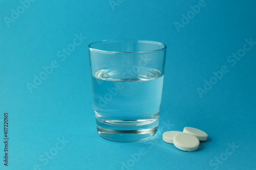 effervescent vitamin C tablet and glass of water on blue background. a glass of water and an effervescent paracetamol tablet.