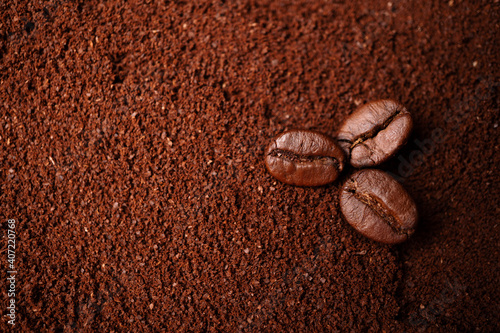 Closeup of three coffee beans at the mixed heap of roasted coffee with copy space for text. Concept of Coffee freshness