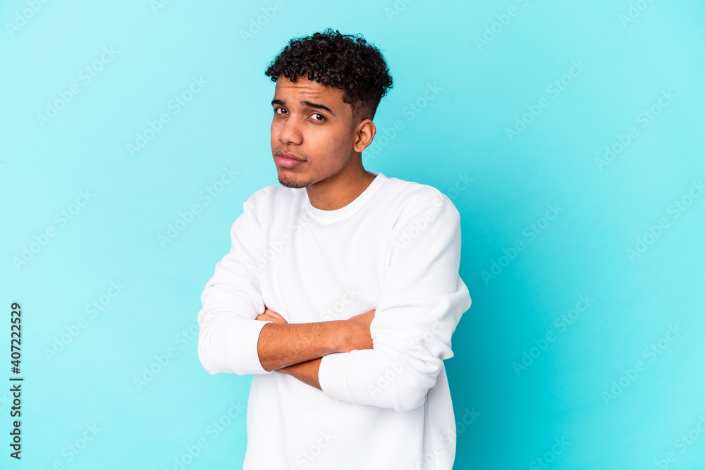 Young african american curly man isolated on blue suspicious, uncertain, examining you. Young african american curly man isolated on blue suspicious, uncertain, examining you.