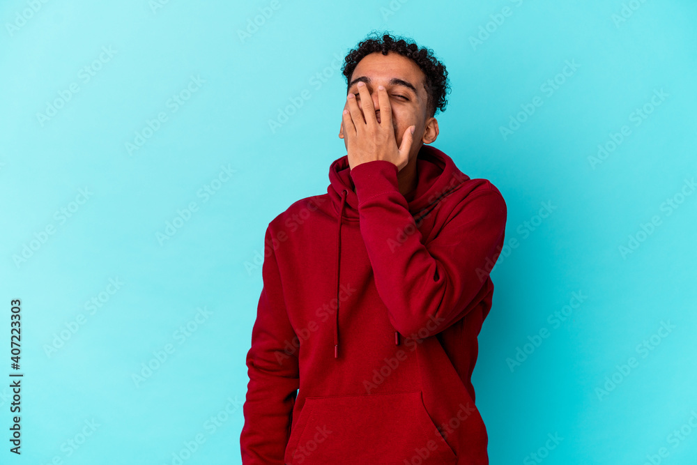 Young african american curly man isolated on blue laughing happy, carefree, natural emotion.