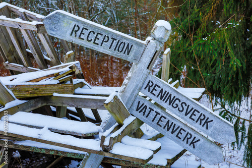 Solbacka, Sweden Old direction signs in Swedish and outdoor tables piled high at the abandoned Solbacka boarding school. Made famous by Jan Guillou's novel Ondskan, it is now in ruin. photo