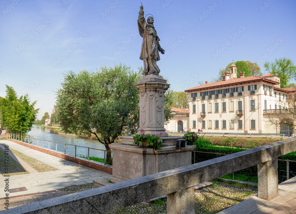 statue and ancient building on the pedestrian cycle track of Cassinetta di Lugagnano, Lombardy, Italy.