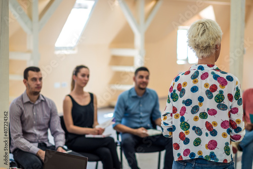 Group of people listening to a presentation. Woman handling the workshop like a pro while speaking on seminar for professional development and team building