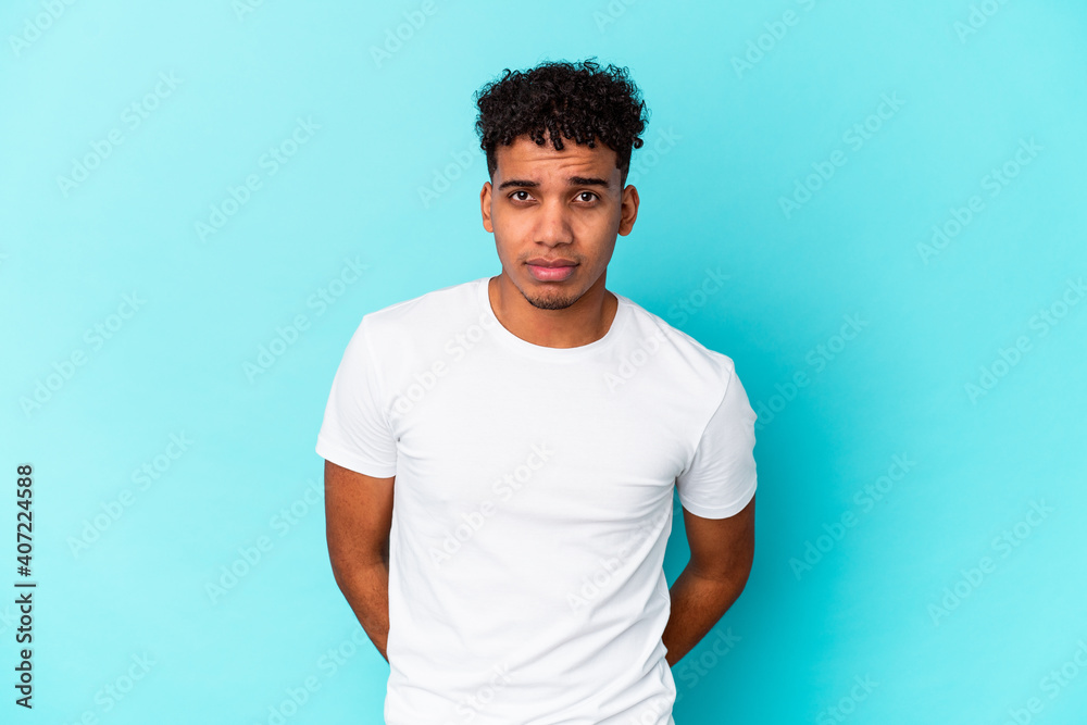 Young african american curly man isolated on blue sad, serious face, feeling miserable and displeased. Young african american curly man isolated on blue sad, serious face, feeling miserable and displeased.
