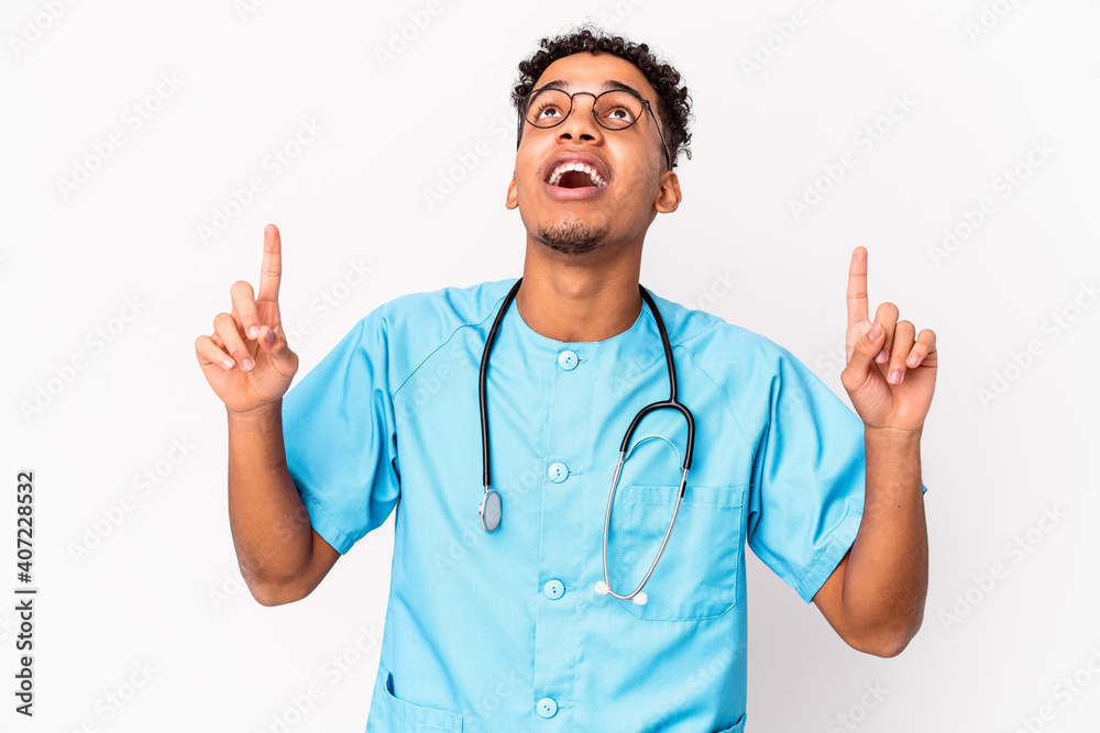 Young african american curly nurse man isolated pointing upside with opened mouth. Young african american curly nurse man isolated pointing upside with opened mouth.