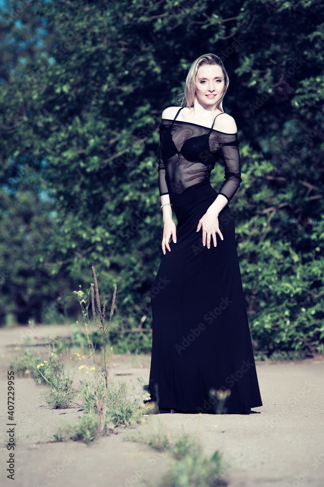 Beautiful sexy blonde girl in black blouse posing in green foliage Beautiful sexy blonde girl in black blouse posing in green foliage