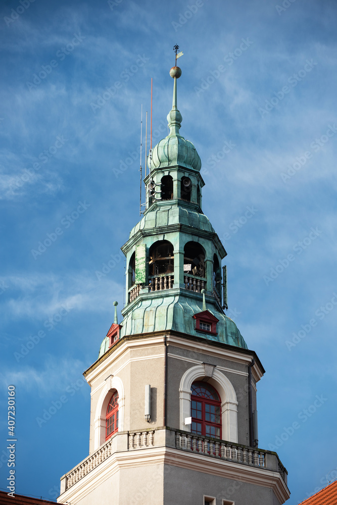 A beautiful building of the town hall with a magnificent tower in the city center of Olsztyn in Warmia, Poland against the background of a blue sky during the day