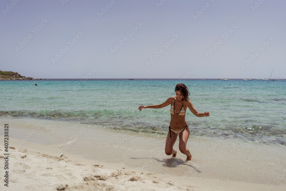 Beautiful young sexy female in bikini on vacation. Enjoying summer time on gorgeous sandy beach with beautiful sea.