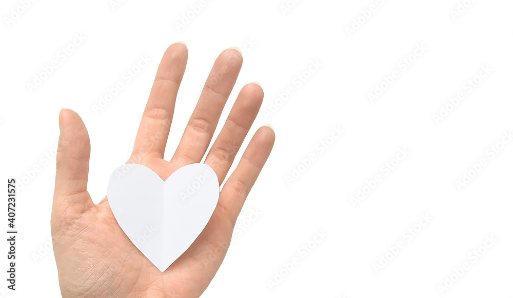 White paper heart in a female hand isolated on a white background White paper heart in a female hand isolated on a white background