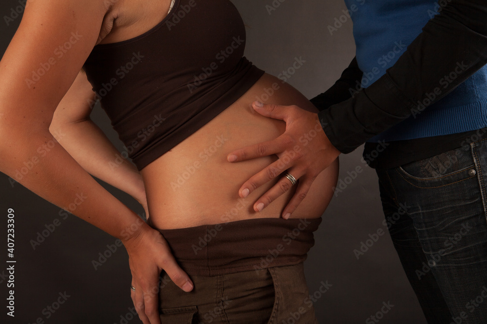 Fototapeta premium Hands and Belly - Pregnant woman belly holding hands of mother, father and child. High quality photo