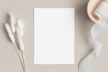 White invitation card mockup with a lagurus on the beige table. 5x7 ratio, similar to A6, A5.