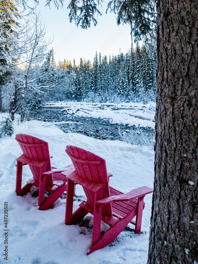 Two red Adirondack chairs nearby Maligne river in winter