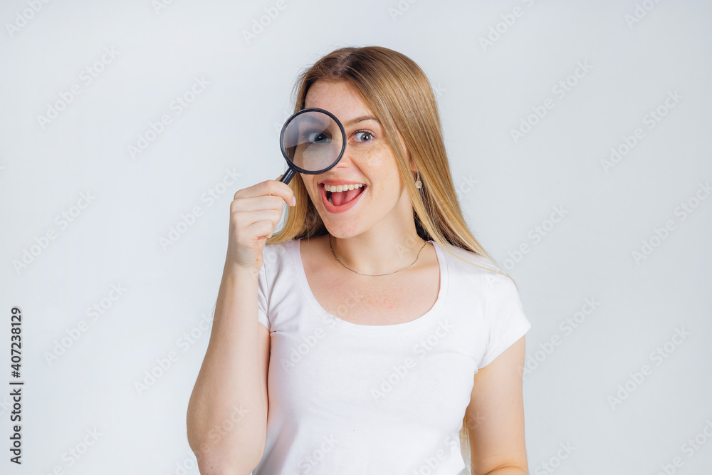 Funny expression. woman looks through a magnifying glass. girl looks amazing revealing evidence with big eyes through a magnifying glass Funny expression. woman looks through a magnifying glass. girl looks amazing revealing evidence with big eyes through a magnifying glass
