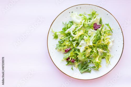 White ceramic plate with fresh salad on light pink background