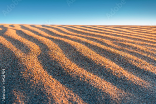 Close-up texture of the rippled surface of the sand and dunes  top view. Desert background