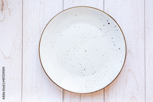 White ceramic plate on wood background, top view