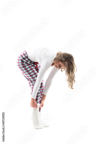 Side view of young woman bending getting dressed in knitted warm winter socks. Full length portrait on white background.