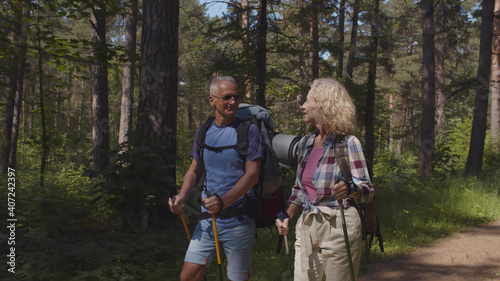 Cute senior couple hiking in summer forest landscape