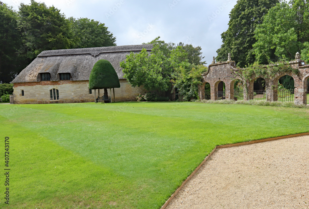 DORCHESTER, DORSET, UK - AUGUST 21ST 2020: A grave path leads round an English stately home, by a lush lawn DORCHESTER, DORSET, UK - AUGUST 21ST 2020: A grave path leads round an English stately home, by a lush lawn