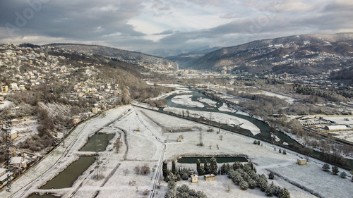 Aerial view of a snow-covered city park. Water intake on the Sochi river in winter. Beautiful view of the mountain peaks in the city.