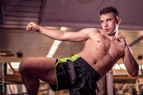 Young handsome kick boxer training hard and preparing for fight, kicking and punching heavy boxing bag. Fighter working out at gym © Vladimir Borovic