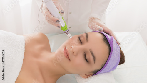 Fractional mesotherapy.A young beautiful woman in the cosmetologist   s office receives fractional mesotherapy for her face. Facial skin rejuvenation. Acne treatment. Hardware cosmetology. Beautician.