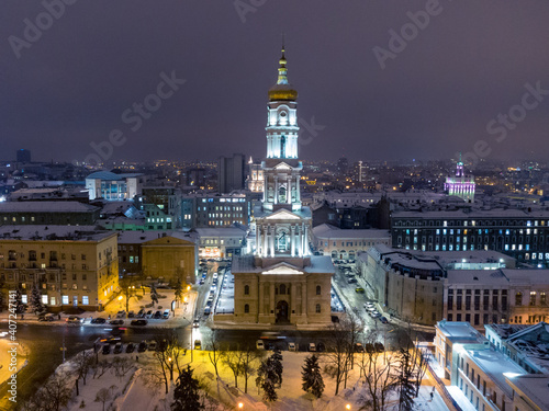 Dormition Cathedral illuminated in winter snowy evening lights. Aerial view Kharkiv city downtown, Ukraine. Front view from air