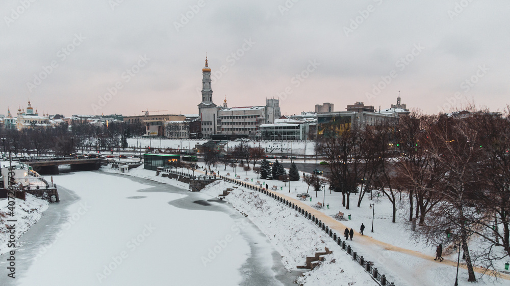 Winter day aerial view on river Lopan embankment and bell tower in Kharkiv Skver Strilka, Ukraine. Urban city snowy cloudy day