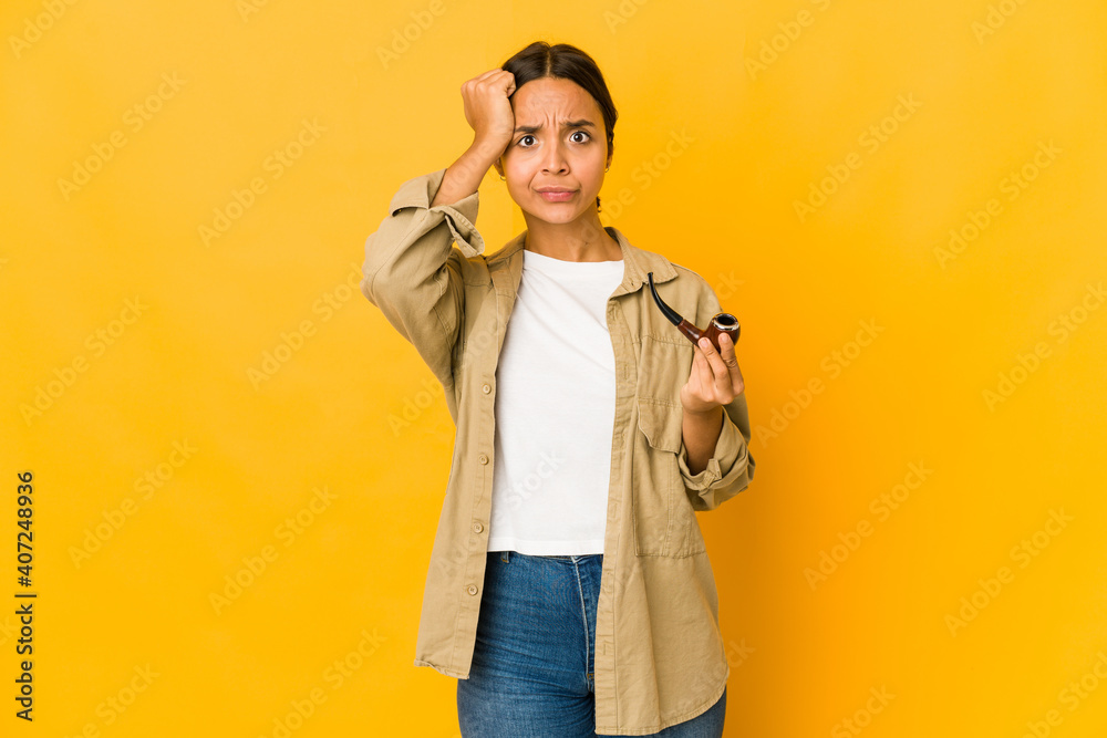 Young hispanic woman holding a smoking pipe being shocked, she has remembered important meeting.