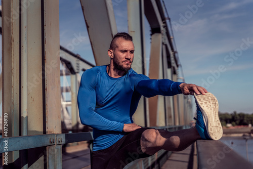 Young handsome man training hard. Man doing sports outside. Outdoors recreation, stretching and training fit body
