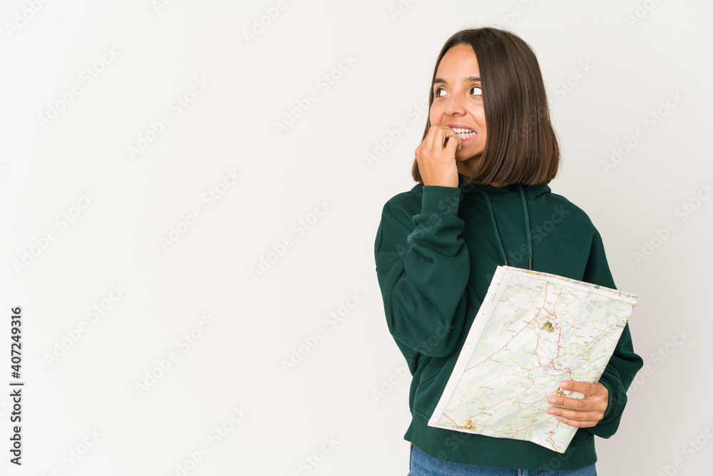 Young hispanic traveler woman holding a map relaxed thinking about something looking at a copy space. Young hispanic traveler woman holding a map relaxed thinking about something looking at a copy space.