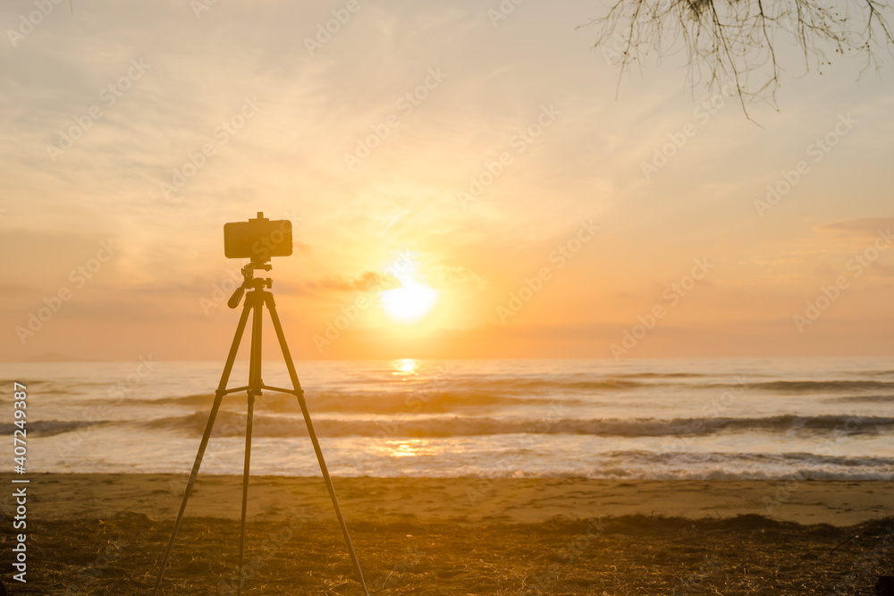 silhouette phone on tripod during record vdo and photo beach with sunrise and sea background silhouette phone on tripod during record vdo and photo beach with sunrise and sea background