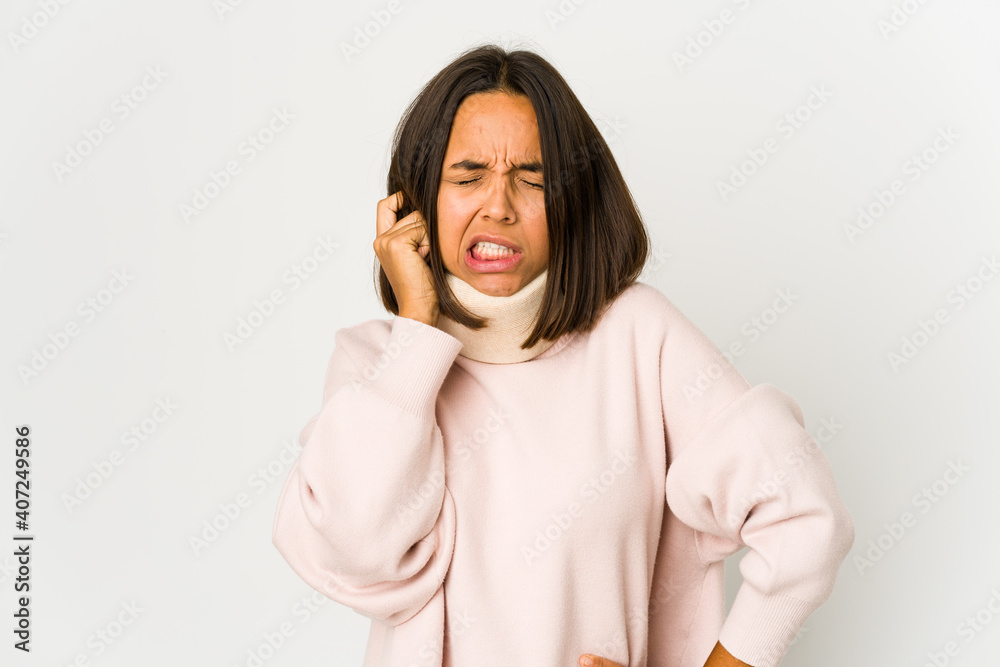 Young hispanic woman wearing a collar covering ears with hands. Young hispanic woman wearing a collar covering ears with hands.