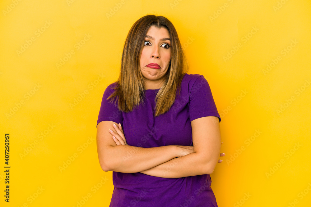Young indian woman isolated on yellow background shrugs shoulders and open eyes confused. Young indian woman isolated on yellow background shrugs shoulders and open eyes confused.