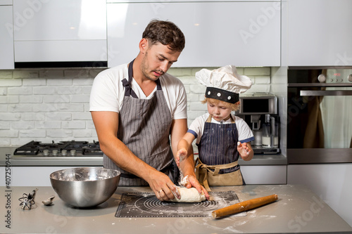 Dad and son kneading dough on the kitchen table.