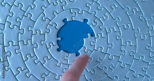 Female hand is putting down gray circular puzzles, pieces, stacking, matching together on blue background. Finishing, completion of work task. Successful achievement of goal. Decision, solution found.