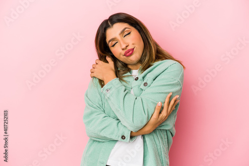 Young indian woman isolated on pink background hugs, smiling carefree and happy. © Asier