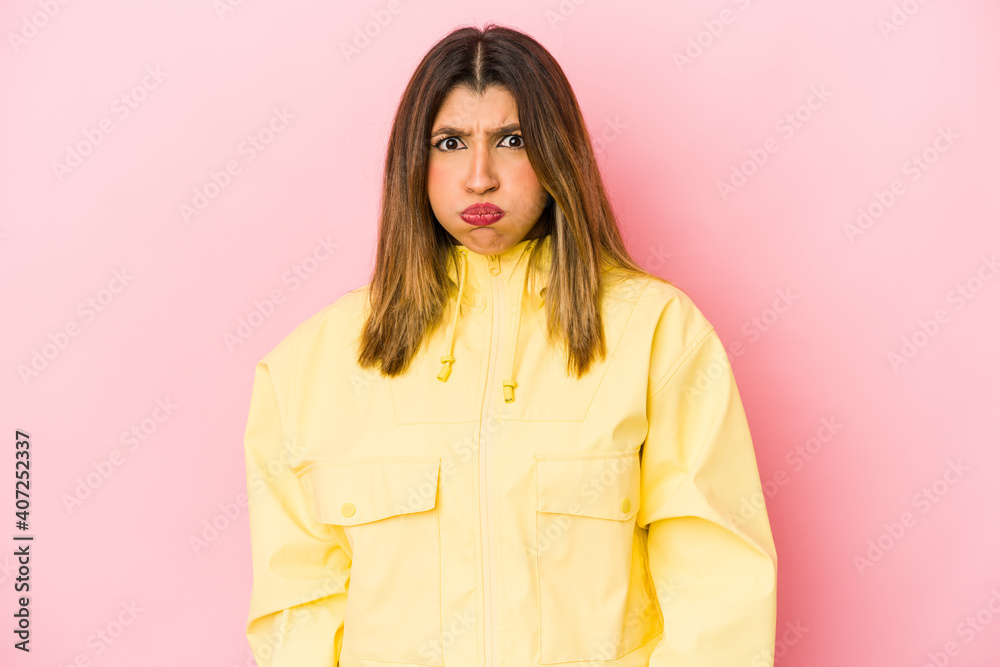 Young indian woman isolated on pink background blows cheeks, has tired expression. Facial expression concept.