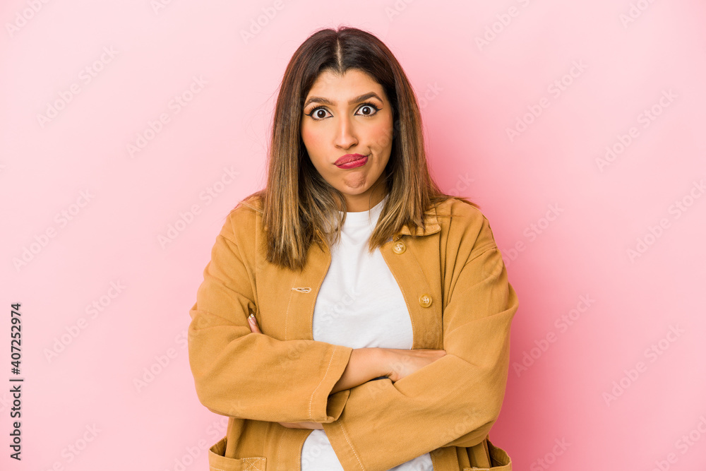 Young indian woman isolated on pink background blows cheeks, has tired expression. Facial expression concept.
