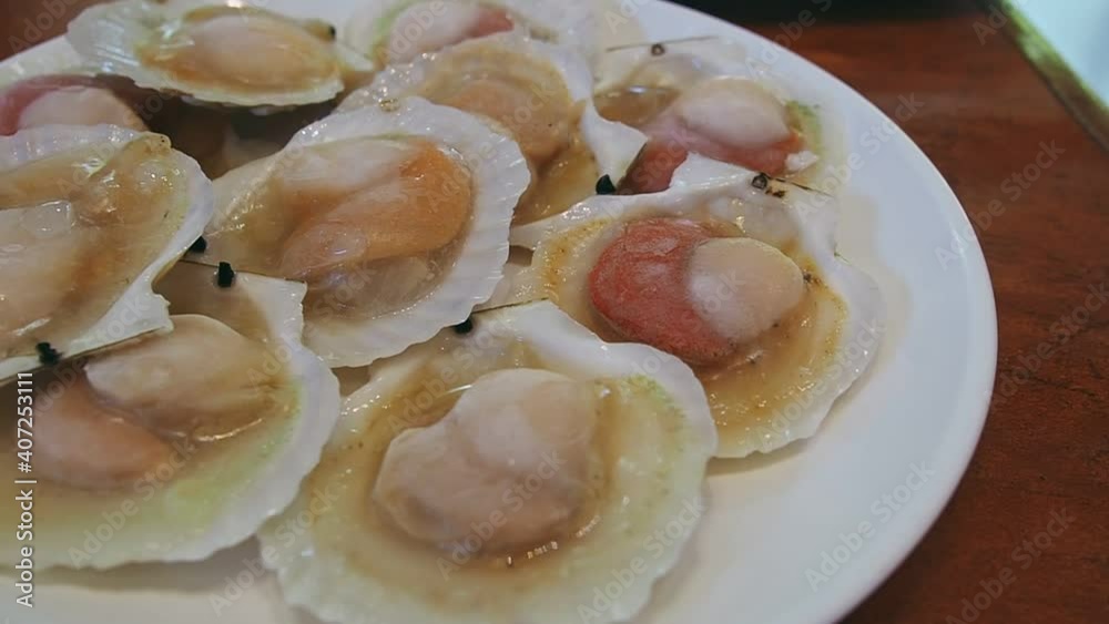 Panning left of raw shellfish or raw scallops on white dish. Japanese cuisine, Sashimi. Panning left of raw shellfish or raw scallops on white dish. Japanese cuisine, Sashimi.