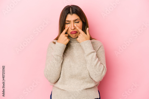 Young indian woman isolated on pink background crying, unhappy with something, agony and confusion concept.