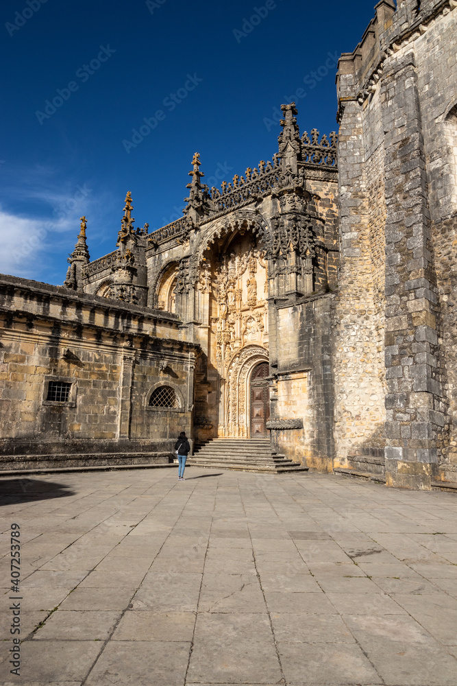 Young traveler enjoying the grandeur of one of the entrance doors of the convent of christ, in Tomar, Portugal