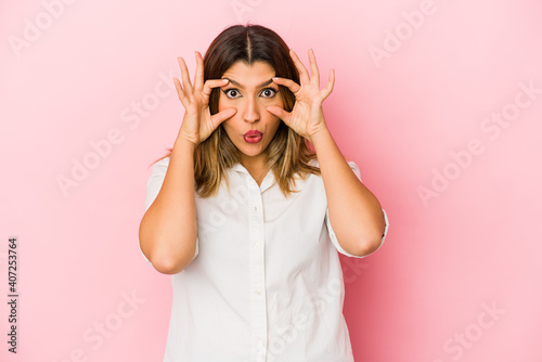 Young indian woman isolated on pink background keeping eyes opened to find a success opportunity.