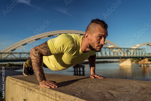 Young handsome man training hard. Man doing sports outside. Outdoors recreation, stretching and training fit body © Vladimir Borovic