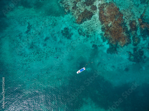 Drone shot of a boat floating near the coral reef barrier Cancun Sardinia rent boat for tourism in summer