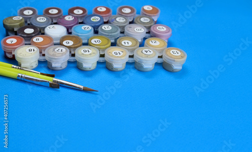 Set of paint and brushes for Painting by numbers on a blue background photo