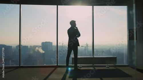 Young Adult Caucasian Entrepreneur Looking into Window Generating New Successful Business Ideas Contemplating Future Staying in Modern Office.