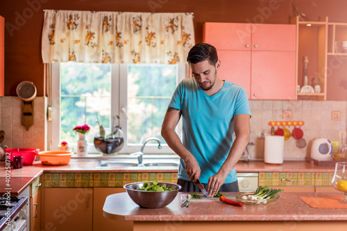 Man in kitchen. Handsome young man with knife in kitchen preparing and cooking vegetarian meal © Vladimir Borovic